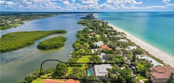 An aerial view of a coastal property with a beach, water bodies, and lush greenery. - Tropical Oasis Estate on Casey Key - Large Pool, Private Dock, Steps to Beach (Nokomis)