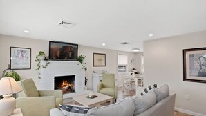 A living room with a fireplace, a sofa, a coffee table, and a TV. - Perfect spot! Cape Cod -1 block to beach and bay with views! (Beach Haven)