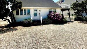 A two-story house with a gravel driveway, a front porch, and a mailbox. - Perfect spot! Cape Cod -1 block to beach and bay with views! (Beach Haven)