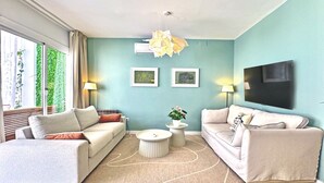 A modern living room with two sofas, a coffee table, and a TV mounted on the wall. - Abbott apartment - 100m2 - 3 bedrooms, living room, 2 terraces, 1 min to beach (Sitges)