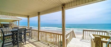 Une terrasse en bois offrant une vue sur la plage et l’océan.