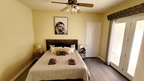 Une chambre à coucher avec un lit, un ventilateur de plafond, une porte et une fenêtre.