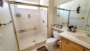 Ein modernes Badezimmer mit einer Duschkabine, einer Toilette und einem Waschbecken mit Ablagefläche.