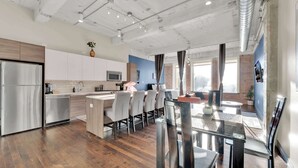 Una cocina moderna con una isla central, electrodomésticos de acero inoxidable y un comedor con mesa y sillas de vidrio.