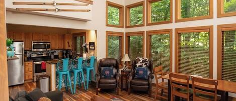 A spacious living area with a kitchen, dining table, and multiple chairs.