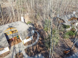 Une maison dotée d’une allée incurvée originale et d’un petit jardin entouré d’arbres.