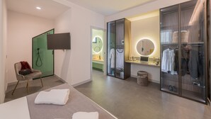 A modern hotel room with a bed, a seating area, a vanity with a mirror, and a wardrobe with a television. - In the heart of the town (Taormina)