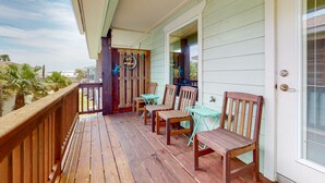 En træterrasse med udendørs møbler og en dør med et skilt.