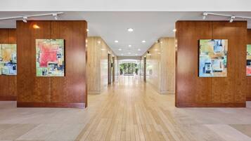 A hallway with wooden paneling and artwork on the walls, leading to a glass door at the end.