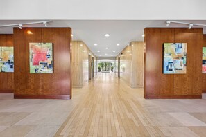 Un pasillo con paneles de madera y obras de arte en las paredes, que conduce a una puerta de cristal al final.