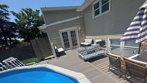En have med swimmingpool, overdækket terrasse og udendørs møbler.