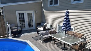 Et poolområde med et glastopbord, fletstole og en stribet parasol.