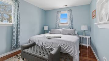 A bedroom with a bed, two bedside tables, a chair, and a window with curtains.
