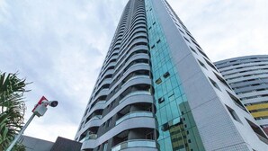 A tall, modern building with a curved facade and multiple balconies. - Apart em Ponta Negra por Carpediem (Natal)
