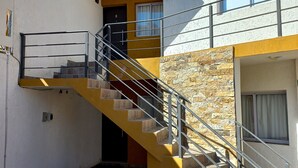 Un edificio de varios niveles con una escalera amarilla, un muro de piedra y una puerta marcada con el número 3.