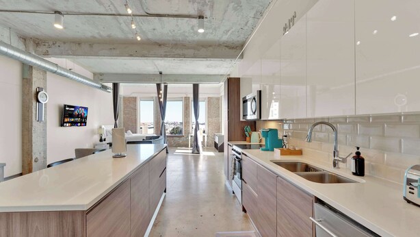 A modern kitchen with a central island, stainless steel appliances, and a view to the outside. - Spacious Downtown Loft | Free Breakfast & Pool (Dallas)