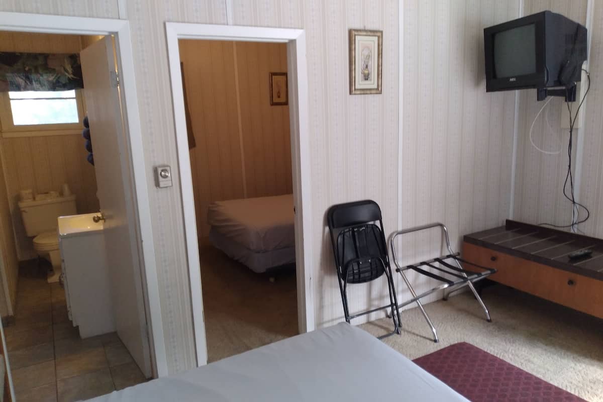 A hotel room with a bed, a chair, a television, and a small desk.