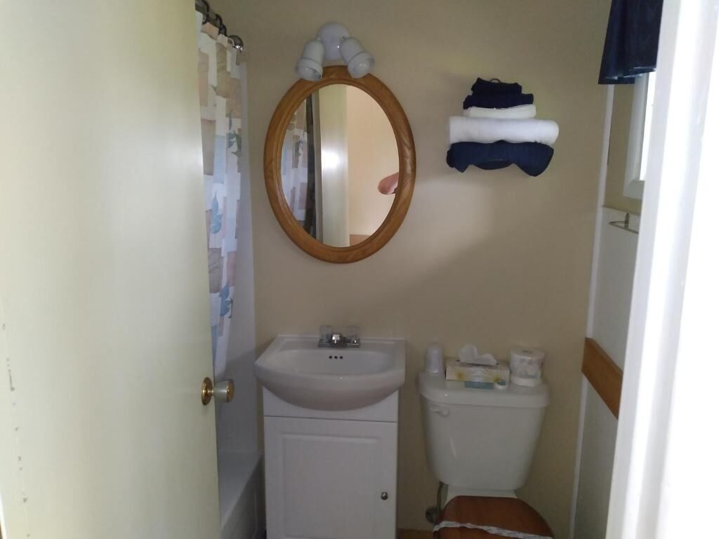 Un baño pequeño con lavamanos, espejo, inodoro y un perchero para toallas.