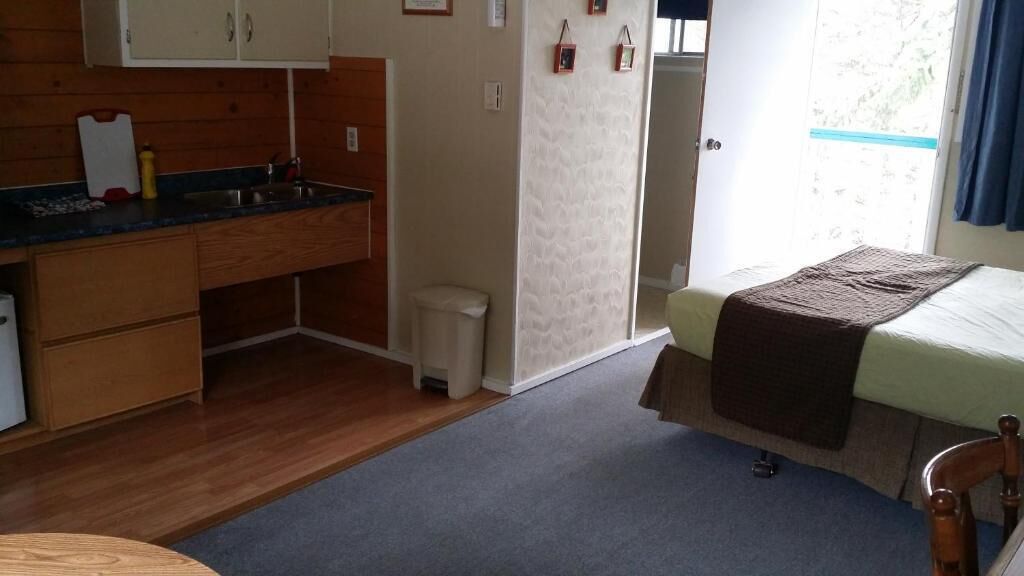 A compact room with a kitchenette, a bed, and a small bathroom.