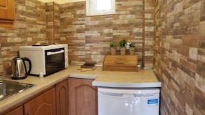 A compact kitchen with a microwave, toaster, and coffee maker on the counter, a small sink, and a white refrigerator. - Corfu Escape Three (Corfu)