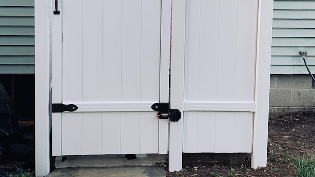 Une porte en métal blanc, dotée de charnières noires et d’un loquet.