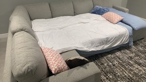 A grey sofa with a white mattress and patterned pillows. - Studio Basement Central El Paso (El Paso)