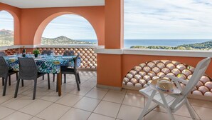 Comedor con una mesa lista para cuatro, con vistas panorámicas al mar y las colinas.