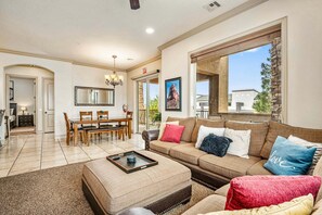 Un amplio salón con una mesa de comedor, un conjunto de sofás y un gran ventanal con vistas al exterior.