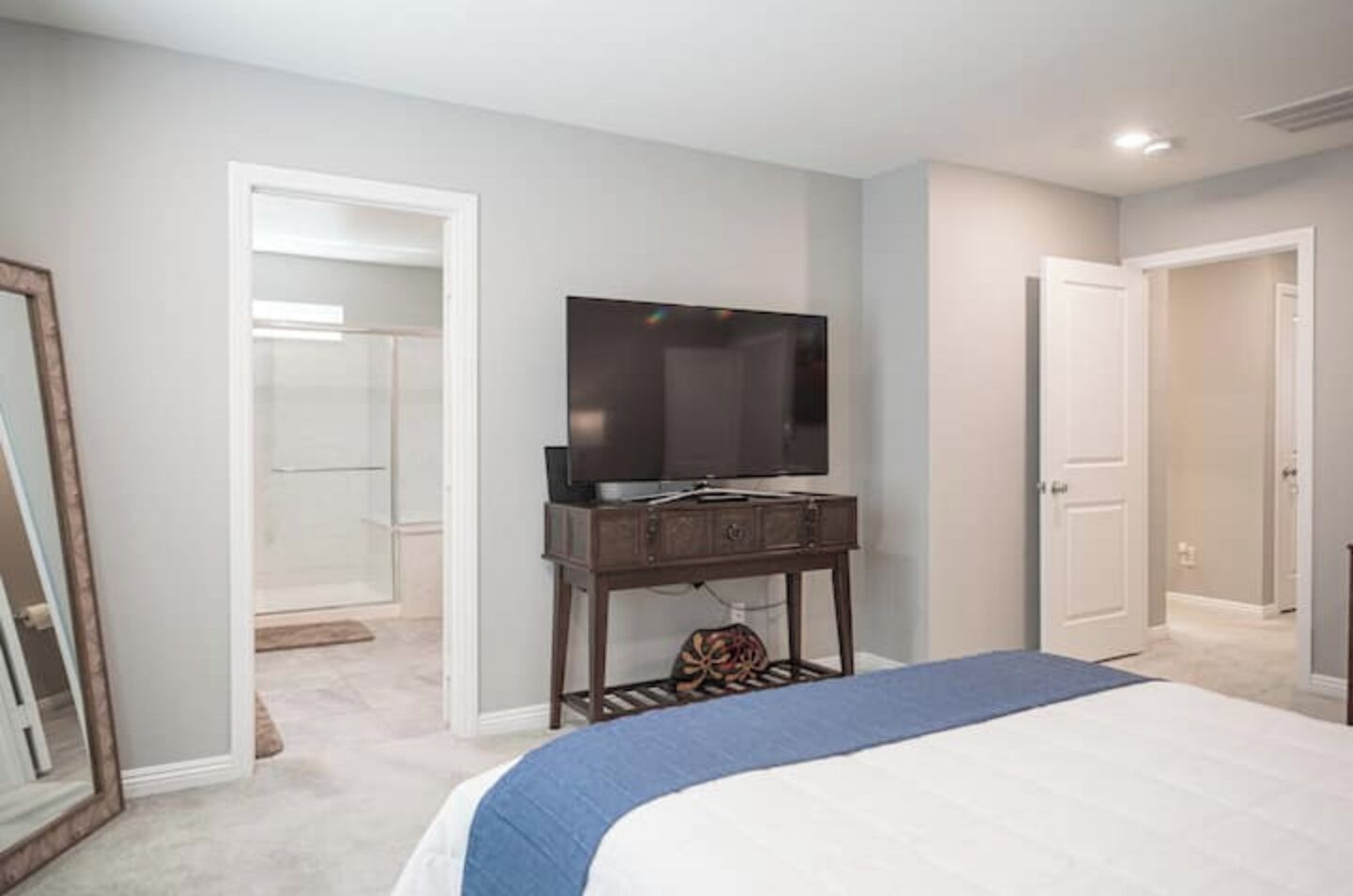 A bedroom with a bed, a dresser, a television, and a walk-in closet.