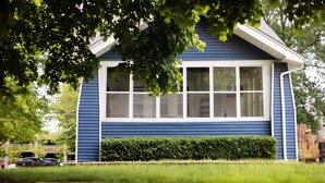 Une maison bleue avec des boiseries blanches, de grandes fenêtres et une pelouse bien entretenue.