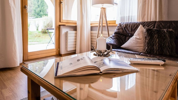 Un salon moderne avec une table basse en verre, un livre, une télécommande et une bougie posée sur un chandelier.