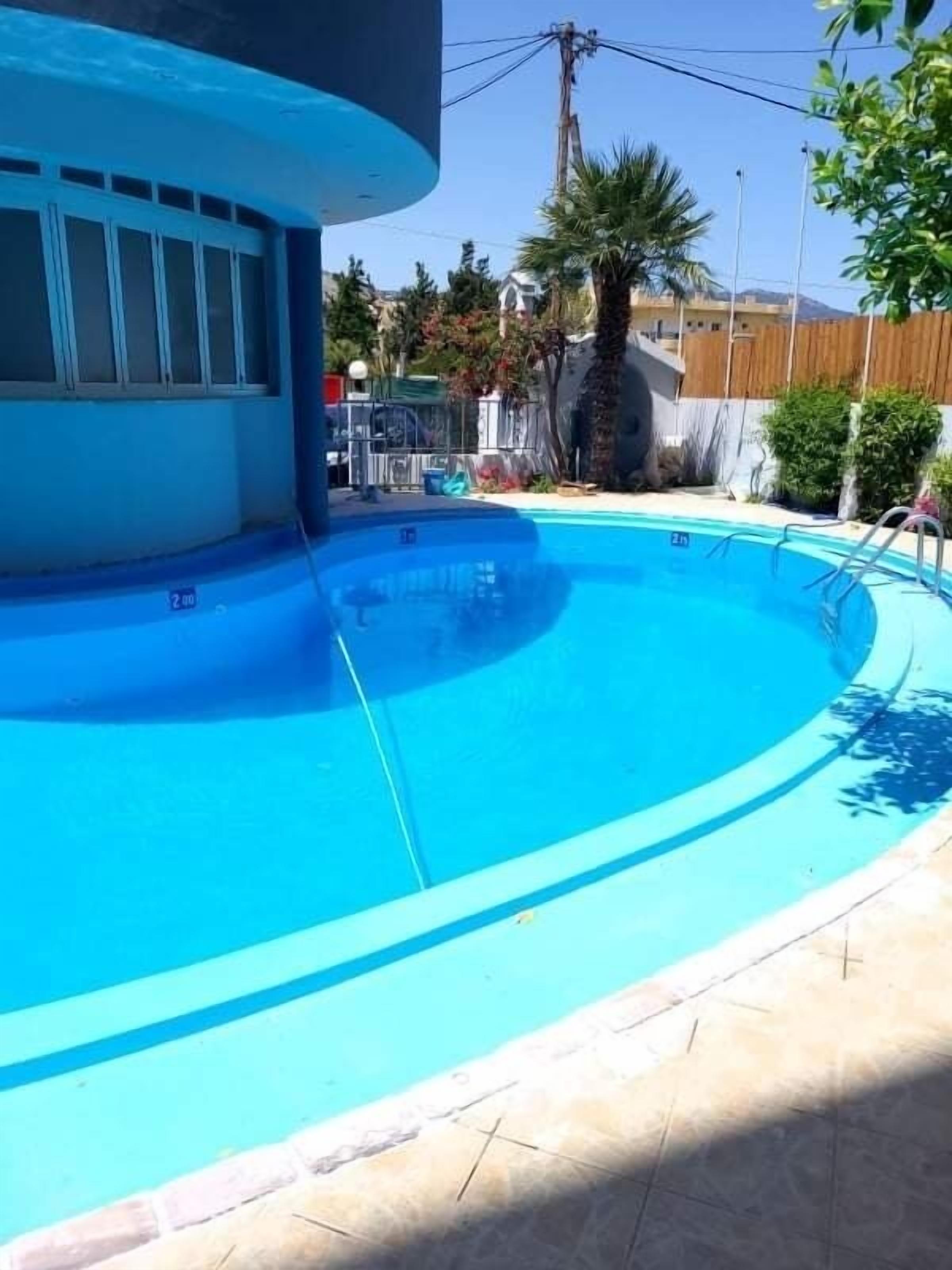 A swimming pool with a curved edge, surrounded by a tiled deck.