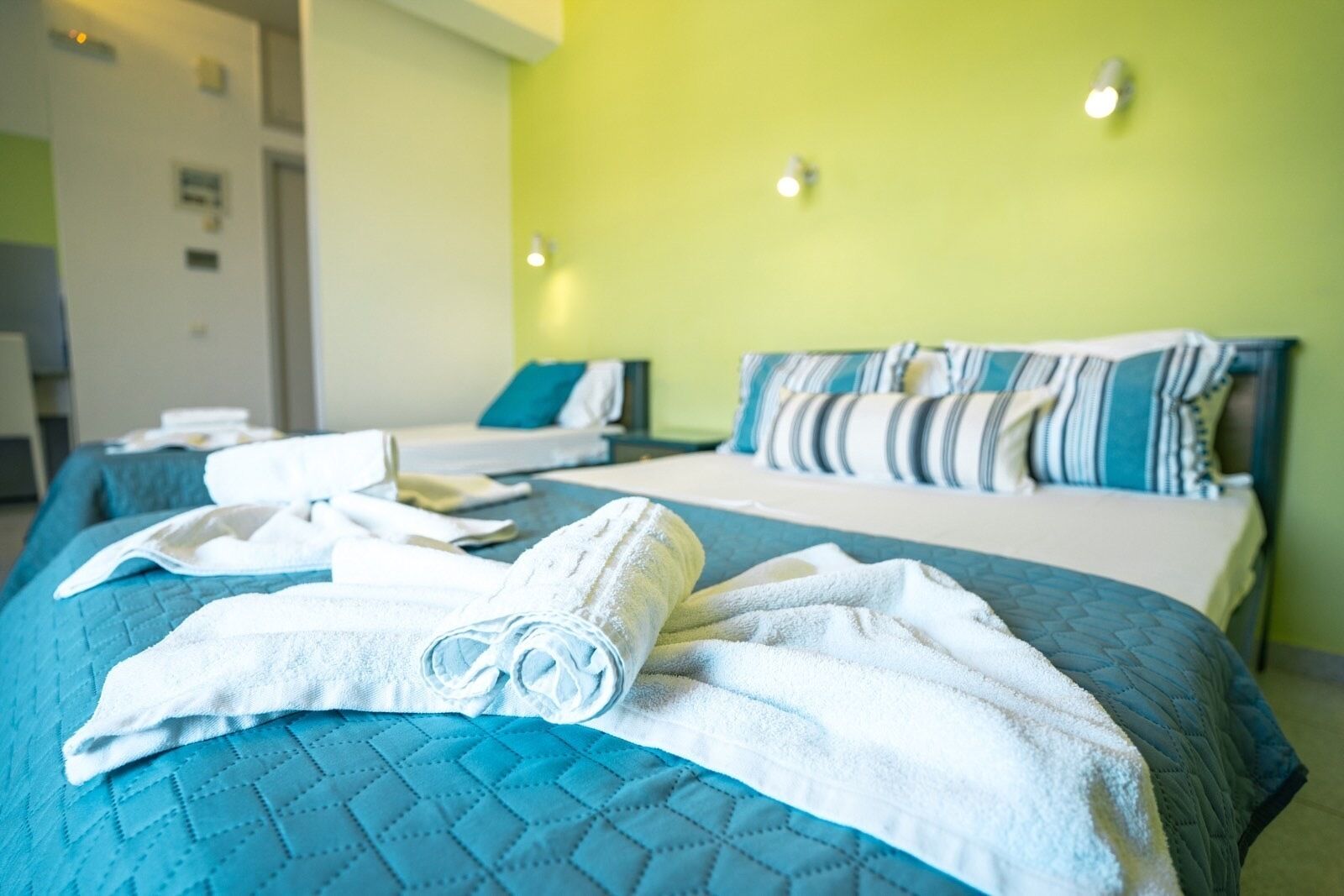 A hotel room with a bed, a second bed, and a bathroom.