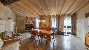 Un comedor espacioso con una mesa y sillas de madera, una chimenea y vistas al exterior.