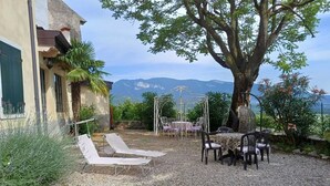 Un patio con mobiliario exterior, una pérgola y vistas a montañas.