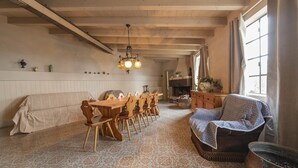 Un comedor con una mesa y sillas de madera, piso estampado y una araña.
