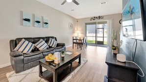 Una sala de estar moderna con un sofá de cuero, una mesa de centro y un comedor con mesa y sillas.