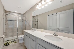 A modern bathroom with a glass-enclosed shower, a double sink vanity, and a large mirror. - ZenHomes (Brandon)