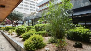 A modern building with a garden area featuring various plants and a gravel path. - Beautiful Loft Area Santiago Bernabeu Madrid (Madrid)