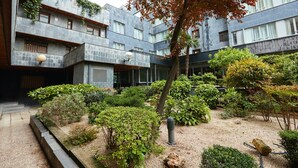 A modern building with a courtyard featuring various plants and a tree with autumn leaves. - Beautiful Loft Area Santiago Bernabeu Madrid (Madrid)