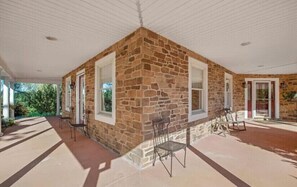 Enjoy a peaceful retreat in this serene outdoor space with a stone wall, windows, and a cozy seating area.