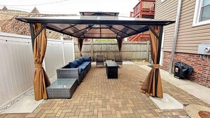 Un área de patio techada con un sofá, sillas y una mesa.
