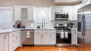 Una cocina moderna con armarios blancos, electrodomésticos de acero inoxidable y suelo de madera.