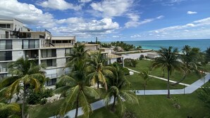 Un hôtel situé en bord de mer, doté de nombreux balcons, de palmiers et offrant une vue dégagée sur l’océan.
