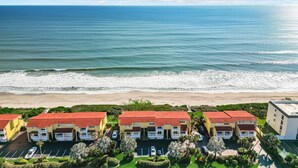 A beachfront hotel with multiple buildings, a parking lot, and a view of the ocean. - Peaceful Beachfront Oasis-- Walk onto the sand! (Melbourne Beach)