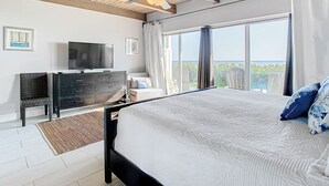 A bedroom with a bed, a TV, a dresser, and a ceiling fan. - Peaceful Beachfront Oasis-- Walk onto the sand! (Melbourne Beach)