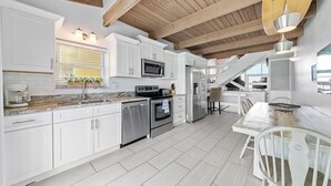 A modern kitchen with white cabinets, stainless steel appliances, and a wooden ceiling. - Peaceful Beachfront Oasis-- Walk onto the sand! (Melbourne Beach)