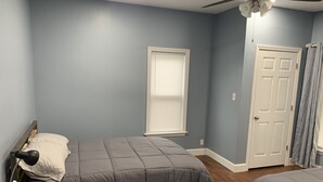 A bedroom with two beds, a ceiling fan, a window with blinds, and a door. - Cheerful 3 bedroom, 2 bath home. (Nelsonville)