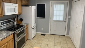 A kitchen with wooden cabinets, a stainless steel oven, a white refrigerator, and a microwave. - Cheerful 3 bedroom, 2 bath home. (Nelsonville)