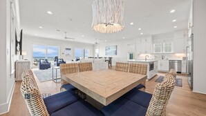 A spacious living area with a large wooden table, wicker chairs, and a view of the ocean. - Ocean Edge 9 | Beach Front, Plunge Pool, Boardwalk | Paradise Found by Kaiser (Orange Beach)